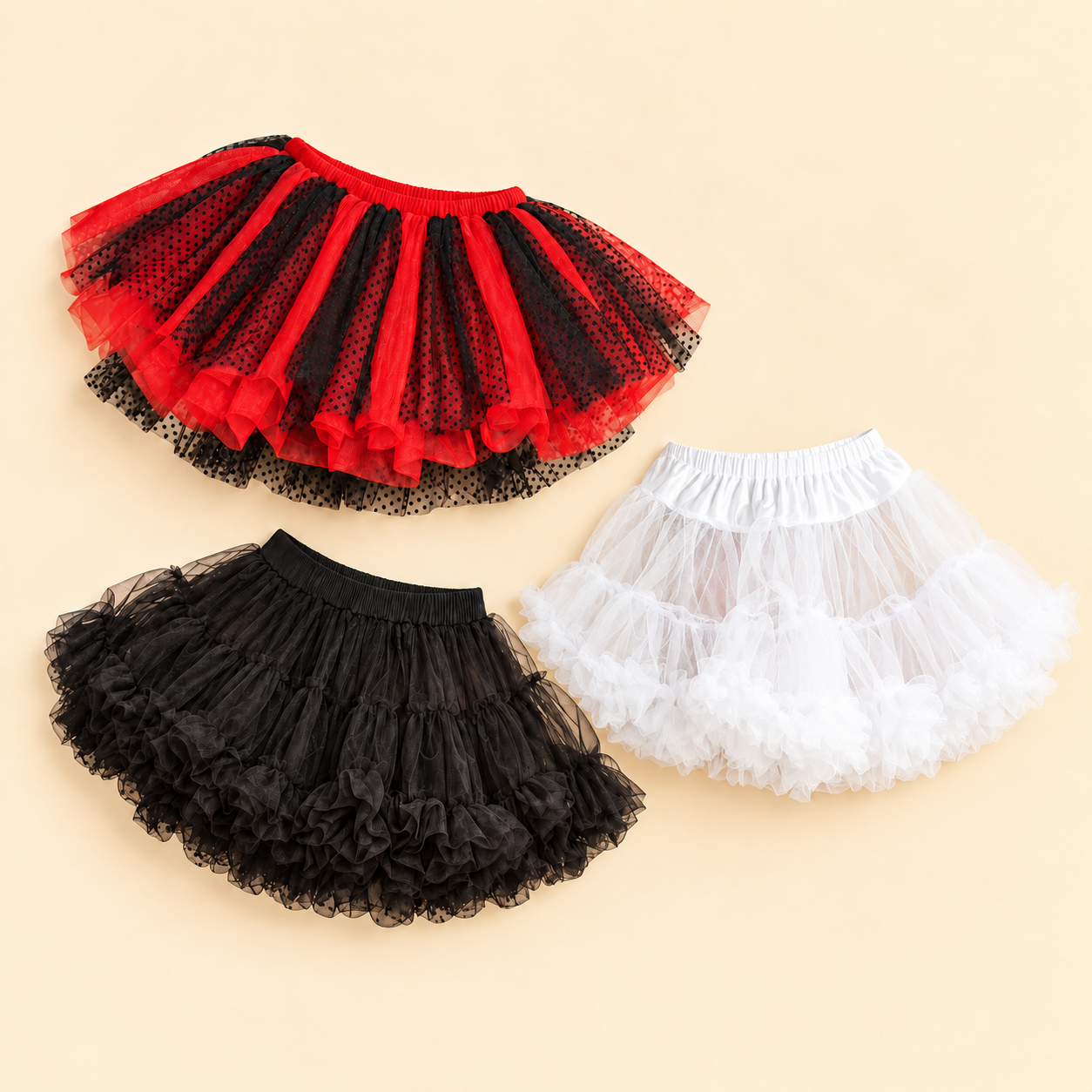 Red and black dotted tutu, black ruffled mini petticoat, and white layered tulle petticoat on a cream background.